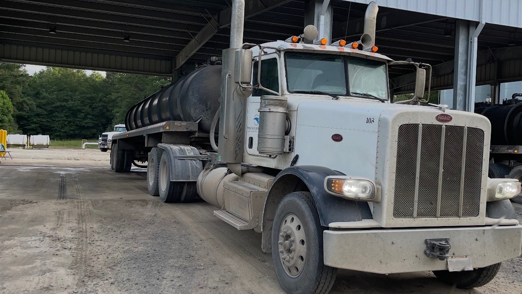 Oilfield tanker truck staged under a covered service bay